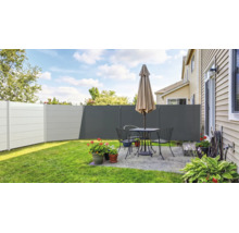Clôture brise-vue moderne en plastique de différents tons gris sur une terrasse entretenue avec salon de jardin, parasol et plantes.