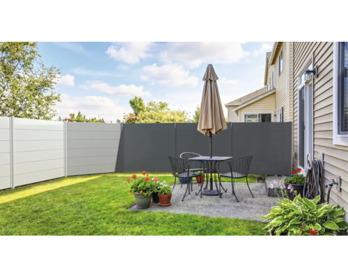 Clôture brise-vue moderne en plastique de différents tons gris sur une terrasse entretenue avec salon de jardin, parasol et plantes.