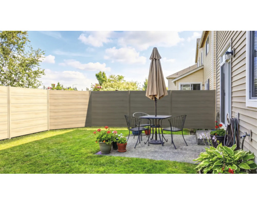Clôture brise-vue moderne composée de panneaux horizontaux dans un jardin avec terrasse, salon de jardin et parasol sur une pelouse soignée.
