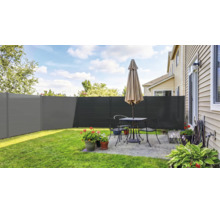 Clôture brise-vue moderne en anthracite sur une terrasse lumineuse avec meubles de jardin, pots de fleurs et pelouse.