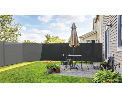 Clôture brise-vue moderne en anthracite sur une terrasse lumineuse avec meubles de jardin, pots de fleurs et pelouse.