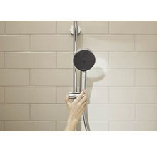 Hansgrohe Handbrause an einer Duschstange montiert, bedient von einer Hand vor einer gefliesten Wand.