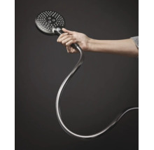 Une main tient une douchette ronde avec flexible.