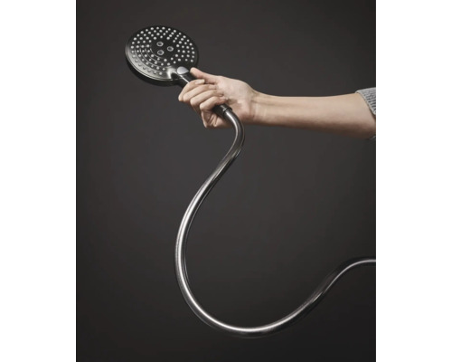 Une main tient une douchette ronde avec flexible.