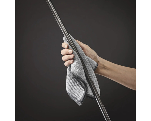 Une main tient un chiffon en microfibre et nettoie une tige métallique avec des gouttes d eau.