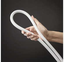 Une main tient un tuyau en plastique flexible pour installations sanitaires.