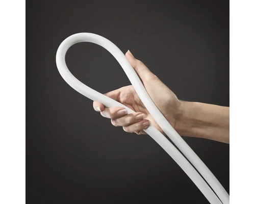 Une main tient un tuyau en plastique flexible pour installations sanitaires.