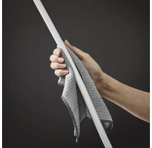 Une main tient un chiffon de nettoyage en microfibre enroulé autour du manche d'une serpillière ou d'un balai.