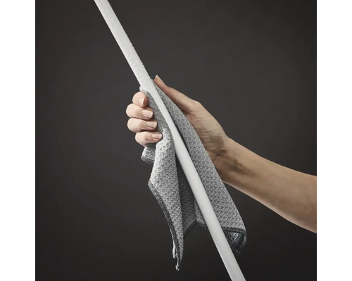 Une main tient un chiffon de nettoyage en microfibre enroulé autour du manche d'une serpillière ou d'un balai.