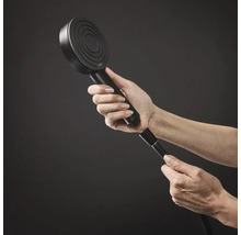 Eine Hand schraubt eine runde Hansgrohe Handbrause an einen Brauseschlauch.