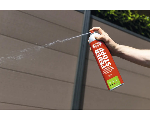 Une main actionne un spray extincteur ABUS Feuer Stopp qui projette un jet.