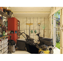 Vue intérieure d'un abri de jardin en bois avec tondeuse autoportée, panneau perforé, étagères et outils de jardin pour un rangement organisé.