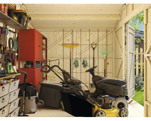 Vue intérieure d'un abri de jardin en bois avec tondeuse autoportée, panneau perforé, étagères et outils de jardin pour un rangement organisé.