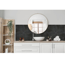 Salle de bain moderne avec meuble vasque, lavabo à poser blanc, miroir rond et revêtement mural sombre aspect pierre en crédence.