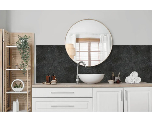 Salle de bain moderne avec meuble vasque, lavabo à poser blanc, miroir rond et revêtement mural sombre aspect pierre en crédence.