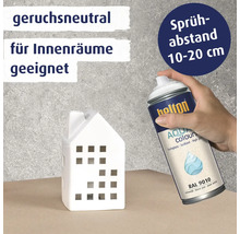 Une main tient une bombe de peinture Belton Aqua Colours pour peindre une petite maison en céramique, avec des conseils sur l'odeur et la distance.