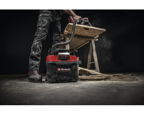 Aspirateur eau et poussières sans fil Einhell utilisé avec une scie circulaire pour travailler le bois sur un établi.