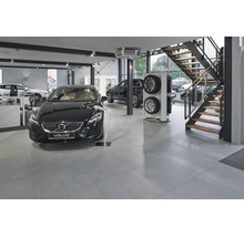 Concessionnaire Volvo moderne avec véhicules d'exposition, présentoir de pneus et un escalier dans un espace de vente spacieux avec carrelage.