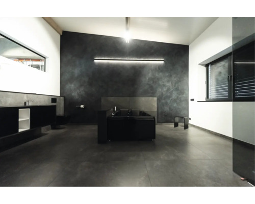 Salle de bains moderne avec baignoire îlot, murs foncés, carrelage au sol grand format et éclairage LED indirect.