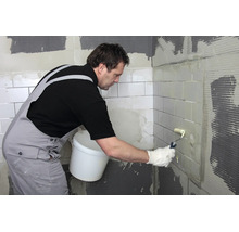 Artisan peint des carreaux avec un rouleau à peinture sur un chantier