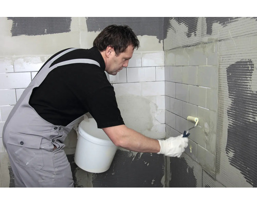 Artisan peint des carreaux avec un rouleau à peinture sur un chantier