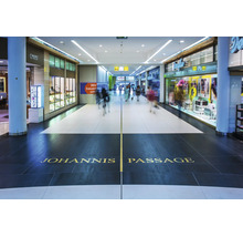 Vue intérieure du Johannis Passage avec des vitrines de magasins et des gens dans un centre commercial moderne.