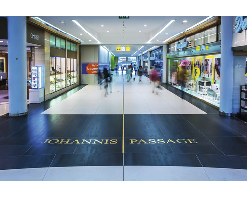Vue intérieure du Johannis Passage avec des vitrines de magasins et des gens dans un centre commercial moderne.