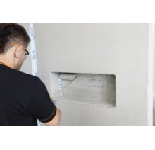 Artisan appliquant de la sous couche avec un rouleau dans une niche murale avec du ruban adhésif PCI