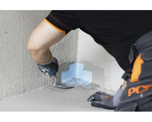 Artisan travaillant une bande d etancheite dans un angle rentrant avec une truelle pour une etancheite murale et au sol professionnelle.