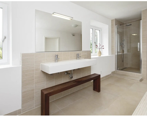 Salle de bain moderne avec double vasque, miroir mural, robinetterie, cabine de douche et un banc en bois devant un mur carrelé clair.