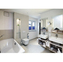 Salle de bain moderne avec double vasque, toilettes suspendues et baignoire dans un aménagement clair avec éclairage indirect.