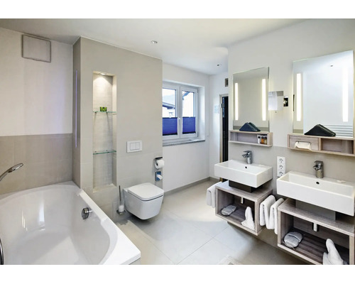 Salle de bain moderne avec double vasque, toilettes suspendues et baignoire dans un aménagement clair avec éclairage indirect.