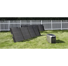Kit de panneaux solaires portables avec station d énergie sur une pelouse devant une clôture en bois blanche.
