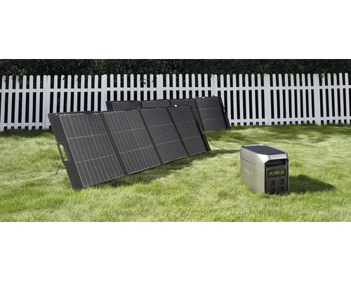 Kit de panneaux solaires portables avec station d énergie sur une pelouse devant une clôture en bois blanche.