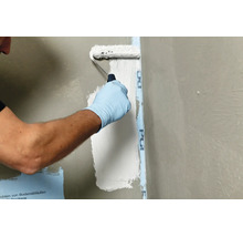 Une personne applique un revêtement d etanchéité liquide sur un mur à l aide d un rouleau pour le rendre imperméable.