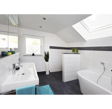 Salle de bain moderne sous pente avec murs carrelés blancs, sol foncé, double vasque et baignoire îlot sous une fenêtre de toit.
