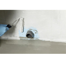 Une personne portant des gants applique un produit d'étanchéité autour d'un tuyau mural avec un rouleau pour assurer l'imperméabilisation.