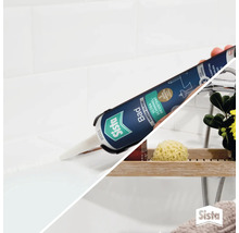 Une main applique du silicone sanitaire pour salle de bain Sista sur un joint de carrelage.