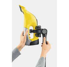 Un nettoyeur de vitres avec kit de rallonge fixé, tenu par des mains.