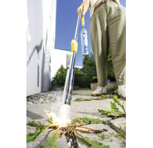 Une personne utilise un désherbeur thermique à gaz pour éliminer les mauvaises herbes sur une surface pavée en extérieur.