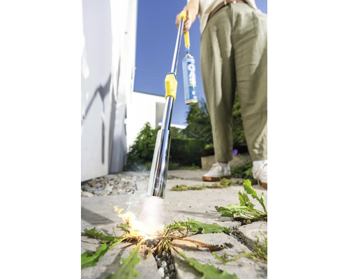 Une personne utilise un désherbeur thermique à gaz pour éliminer les mauvaises herbes sur une surface pavée en extérieur.