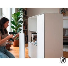 Une femme monte une armoire moderne avec une perceuse sans fil dans un salon. (Image AI modified or generated)
