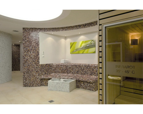 Espace bien-être moderne avec cabine infrarouge, banc carrelé en mosaïque et bain de pieds dans une ambiance élégante et relaxante.