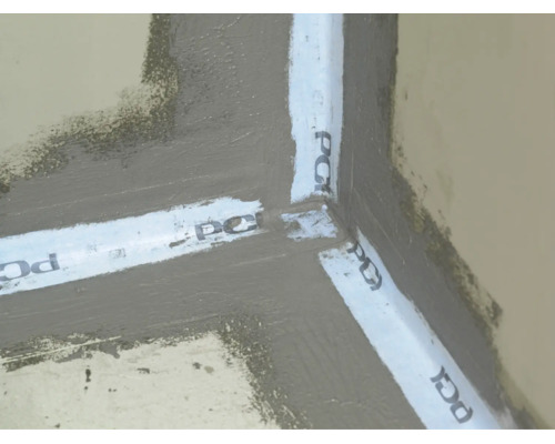 Étanchéité composite avec bande d'étanchéité PCI dans un coin intérieur sur le sol et le mur pour l'étanchéité de la salle de bain.