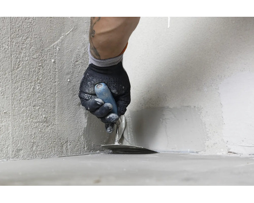 Artisan appliquant du mortier d étanchéité ou de l enduit dans le coin d un mur avec une truelle