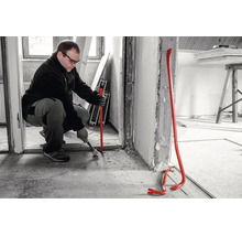 Un artisan utilise un pied de biche lors de travaux de rénovation à l'intérieur.