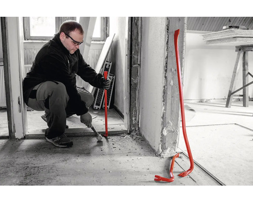 Un artisan utilise un pied de biche lors de travaux de rénovation à l'intérieur.