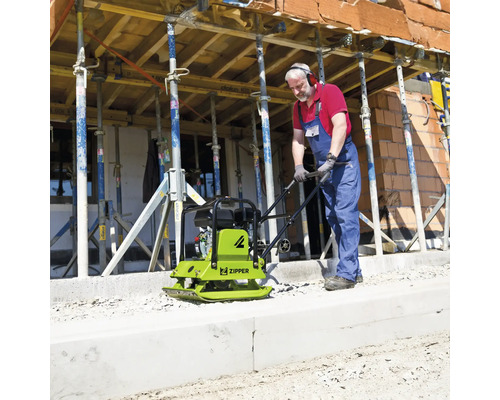 Un ouvrier utilise une plaque vibrante Zipper sur un chantier avec des étais.