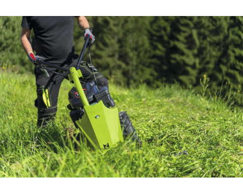 Personne tond une prairie avec une motofaucheuse sur une pente.