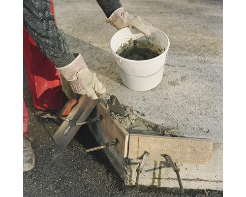 Artisan betonnat un mur avec une truelle et un seau ainsi qu un coffrage en bois sur un chantier.